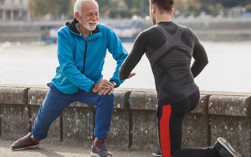 An older man guided through a stretch by a physiotherapist
