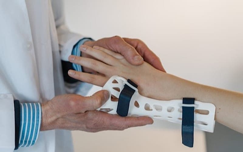 A clinician’s hands fitting a patient’s wrist support